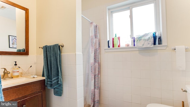 bathroom featuring a shower with curtain, vanity, tile walls, and toilet