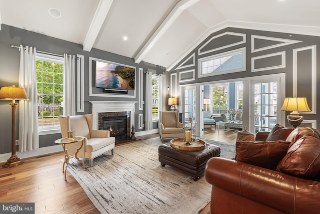 interior space with lofted ceiling with beams, wood-type flooring, a premium fireplace, and a wealth of natural light