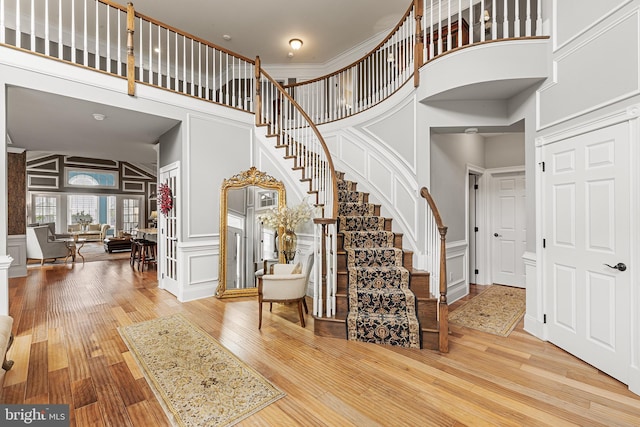 entryway with wood-type flooring and a towering ceiling