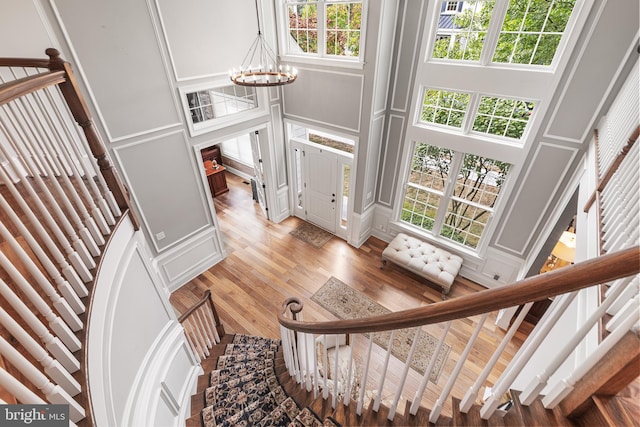 stairway with hardwood / wood-style flooring, a healthy amount of sunlight, a high ceiling, and an inviting chandelier