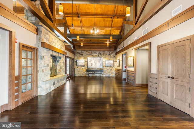 unfurnished living room featuring beamed ceiling, dark hardwood / wood-style flooring, an inviting chandelier, and wooden ceiling