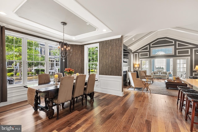 dining area featuring dark hardwood / wood-style flooring, vaulted ceiling, and an inviting chandelier