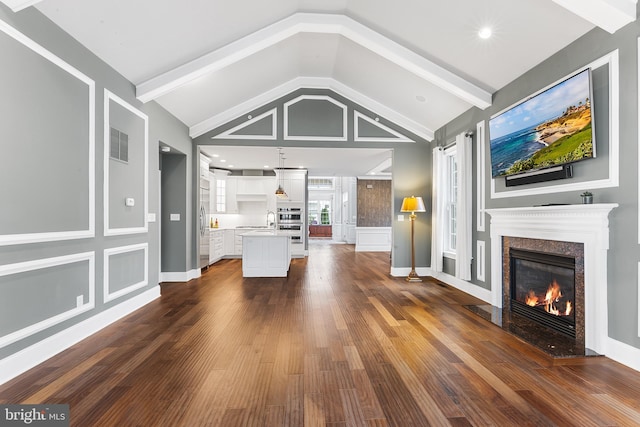 unfurnished living room with sink, dark wood-type flooring, lofted ceiling, and a premium fireplace