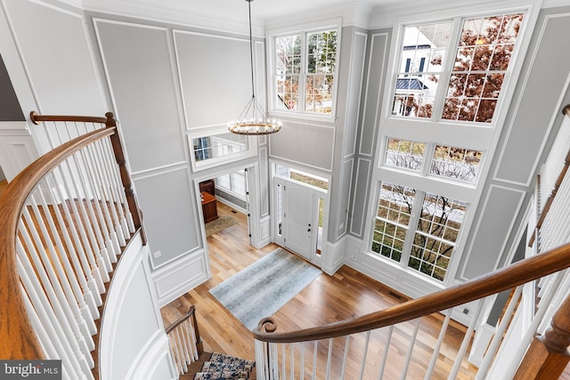 interior space with a notable chandelier, wood-type flooring, and crown molding