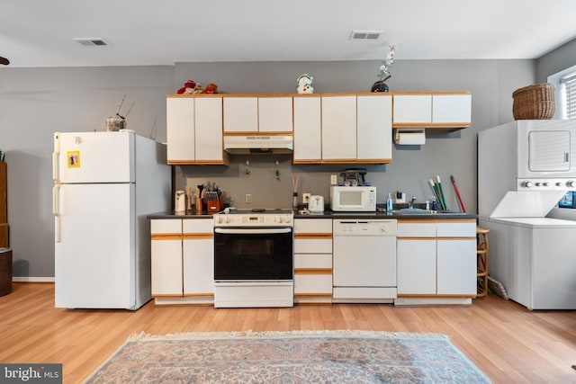 kitchen featuring stacked washer and clothes dryer, sink, white appliances, and light wood-type flooring