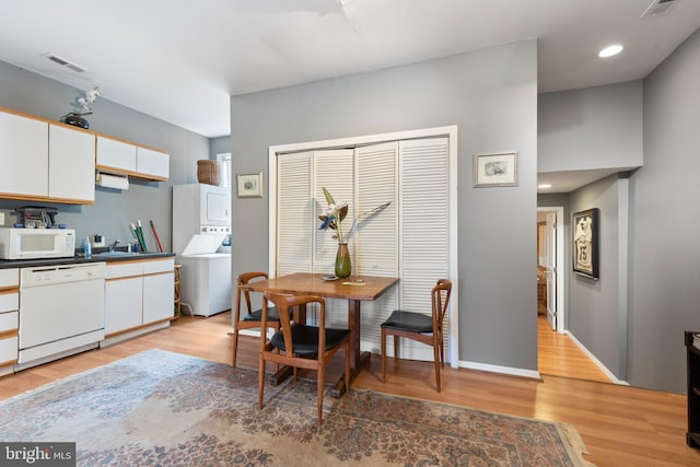 dining room featuring stacked washer and clothes dryer and light hardwood / wood-style flooring