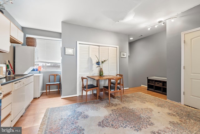 kitchen with white cabinetry, white dishwasher, and light hardwood / wood-style floors