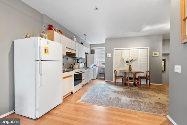 kitchen featuring white cabinets, light wood-type flooring, and white appliances