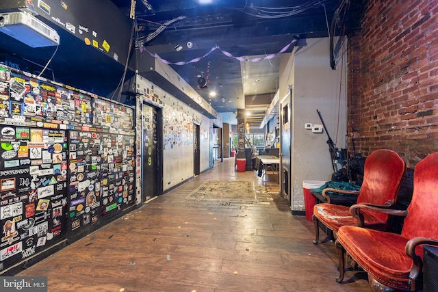 hall featuring hardwood / wood-style floors and brick wall