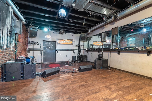 workout room with wood-type flooring and brick wall