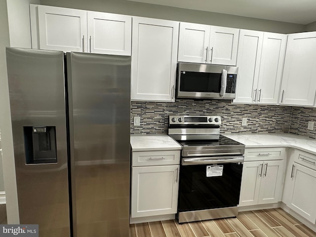 kitchen with light stone counters, white cabinets, stainless steel appliances, and light hardwood / wood-style floors