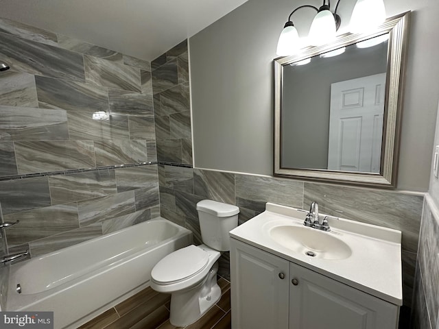 full bathroom featuring tile walls, tiled shower / bath, vanity, and toilet