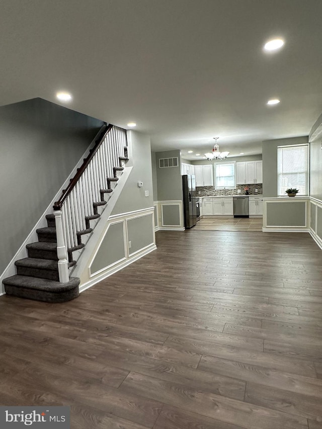 basement featuring an inviting chandelier, dark hardwood / wood-style flooring, stainless steel fridge with ice dispenser, and sink