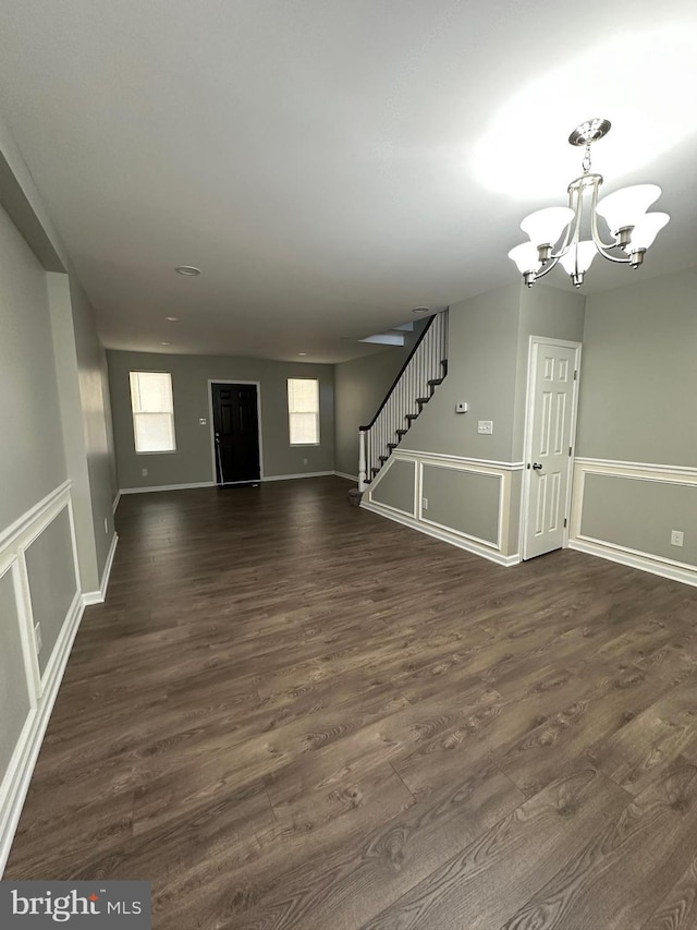 unfurnished living room with a chandelier and dark wood-type flooring