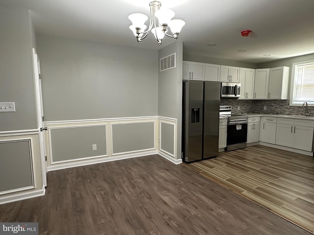 kitchen with appliances with stainless steel finishes, white cabinetry, dark hardwood / wood-style flooring, and sink