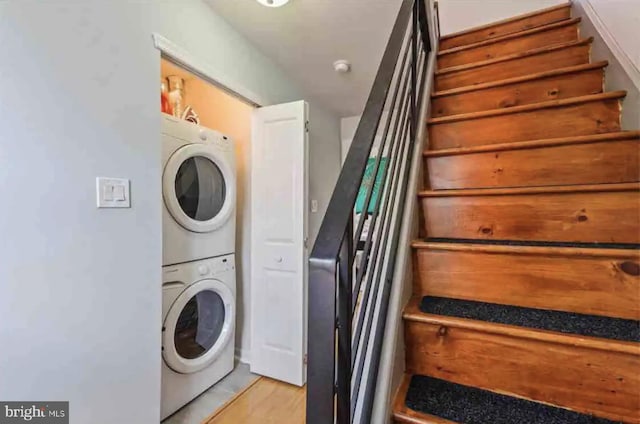 clothes washing area featuring light wood-type flooring and stacked washer and dryer