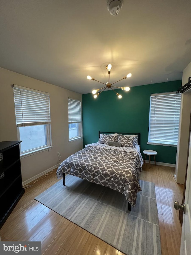 bedroom with wood-type flooring and a notable chandelier