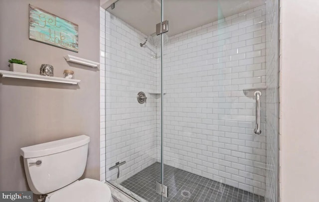 bathroom featuring a shower with shower door and toilet