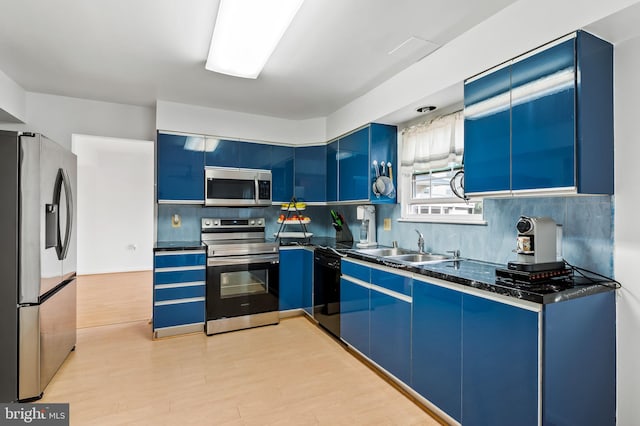 kitchen with light hardwood / wood-style flooring, stainless steel appliances, blue cabinets, and sink