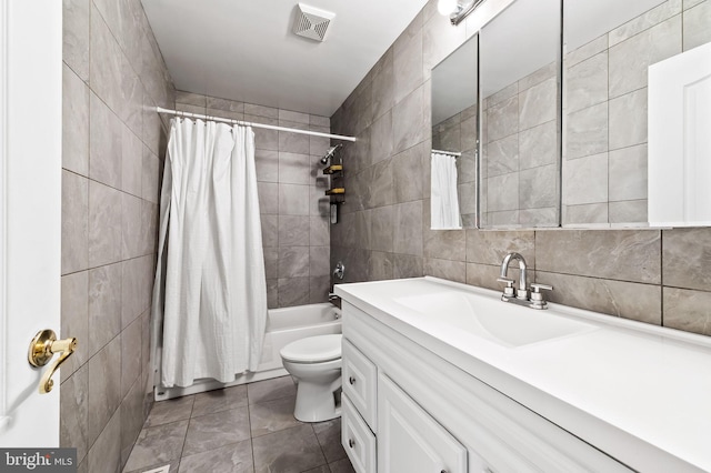 full bathroom with vanity, shower / tub combo, tile patterned floors, tile walls, and toilet