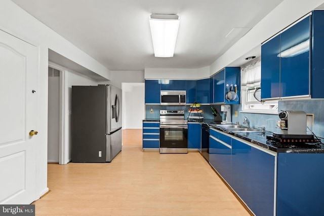 kitchen with appliances with stainless steel finishes, decorative backsplash, blue cabinets, and light wood-type flooring