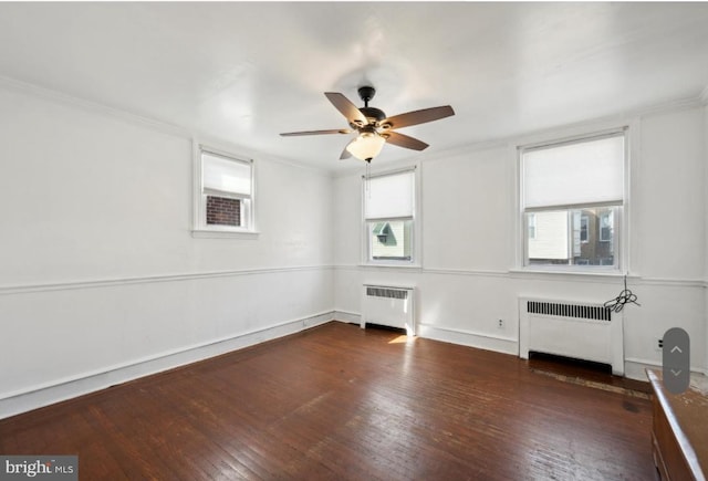 empty room featuring a healthy amount of sunlight, radiator, and dark wood-type flooring