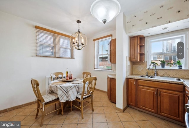 tiled dining room featuring a notable chandelier, a wealth of natural light, and sink