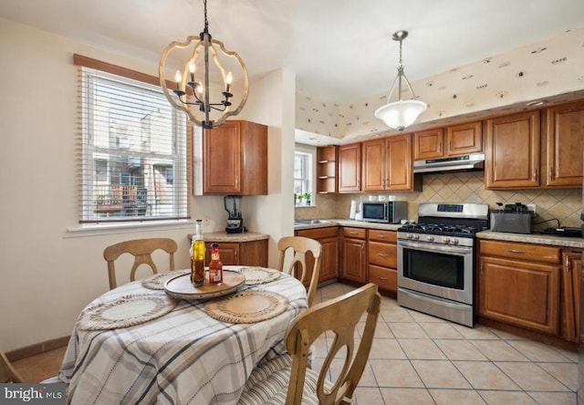 kitchen with appliances with stainless steel finishes, light tile patterned floors, pendant lighting, and tasteful backsplash