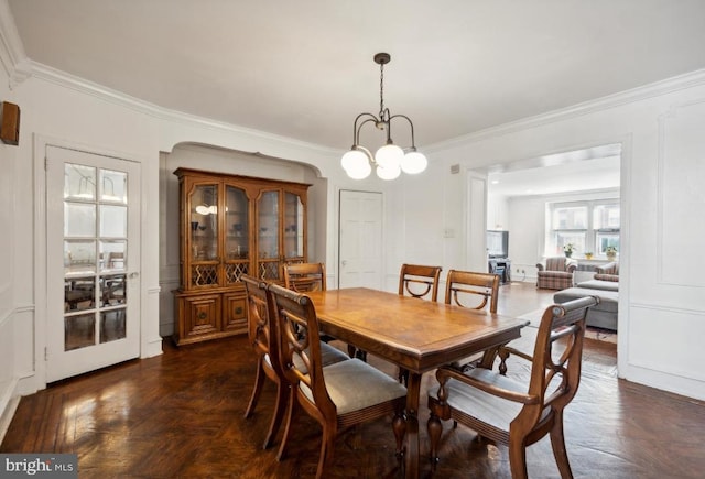 dining area featuring an inviting chandelier, dark parquet flooring, and ornamental molding