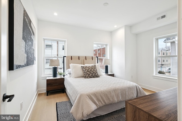 bedroom with light hardwood / wood-style floors and multiple windows