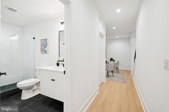 bathroom featuring vanity, a shower, toilet, and hardwood / wood-style flooring