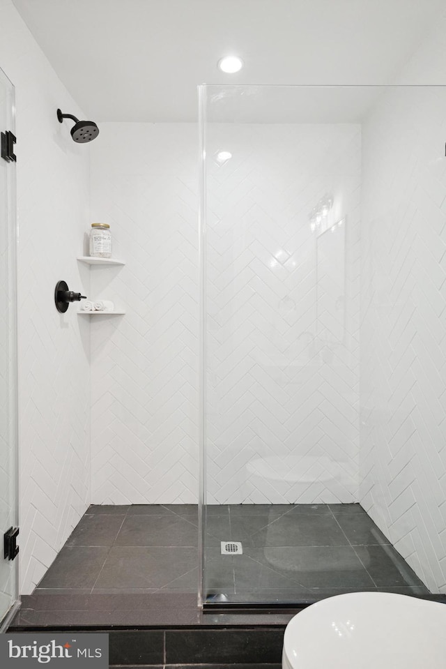 bathroom with a tile shower and toilet