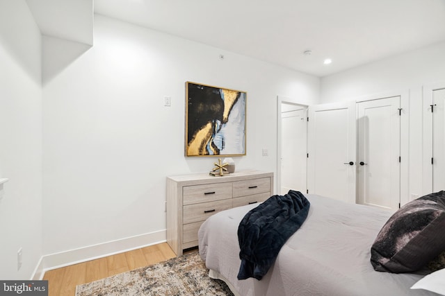 bedroom featuring two closets and light hardwood / wood-style flooring