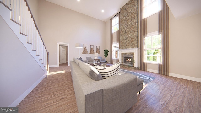 living room featuring hardwood / wood-style flooring, high vaulted ceiling, a healthy amount of sunlight, and a stone fireplace