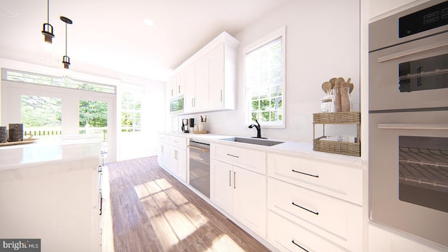 kitchen with white cabinets, appliances with stainless steel finishes, a wealth of natural light, and decorative light fixtures