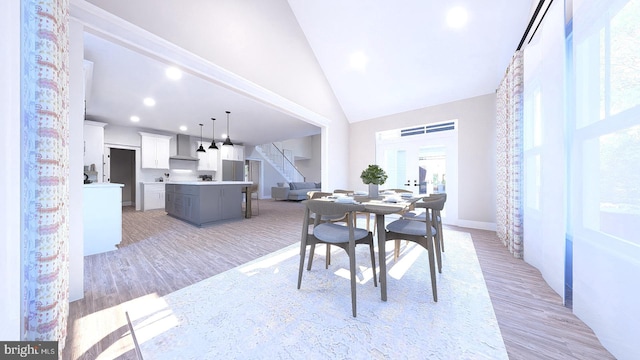 dining area featuring light wood-type flooring and high vaulted ceiling