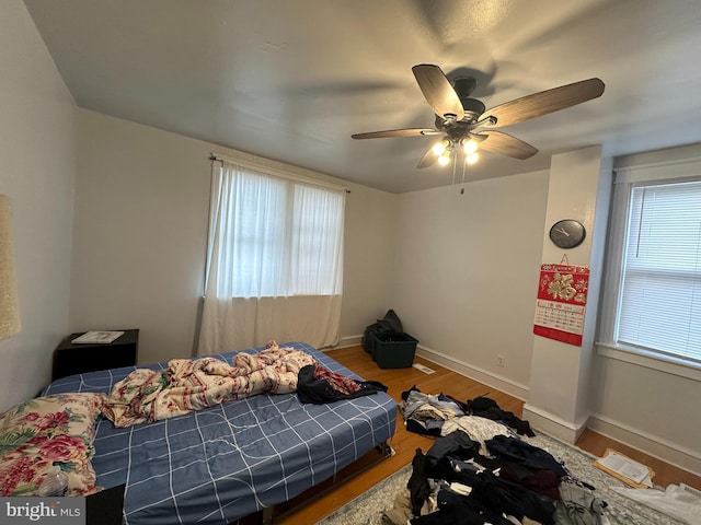 bedroom with ceiling fan, hardwood / wood-style flooring, and multiple windows