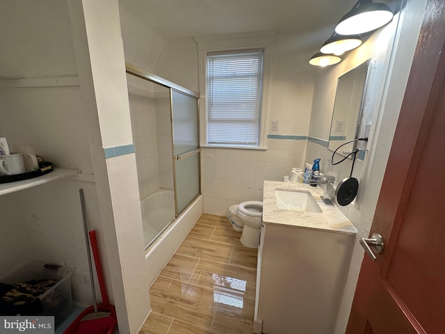 full bathroom featuring tile walls, vanity, shower / bath combination with glass door, and toilet