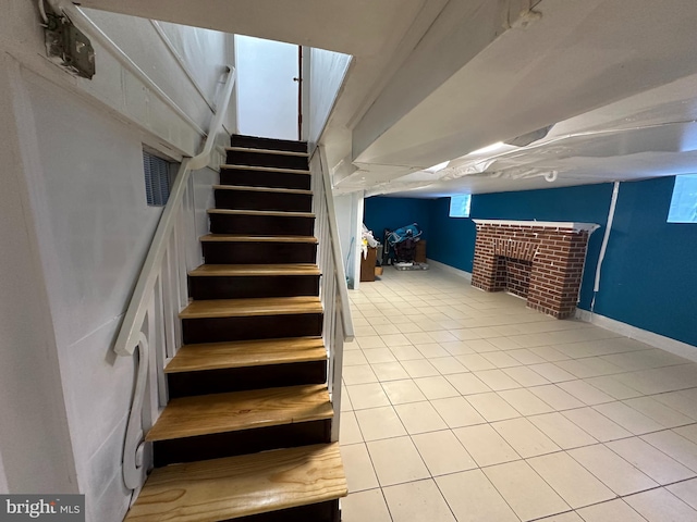 stairs with tile patterned floors and a fireplace