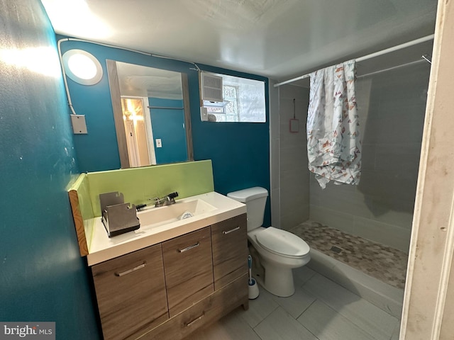 bathroom featuring toilet, vanity, a tile shower, and tile patterned flooring