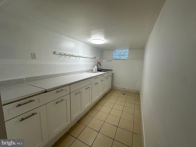 kitchen featuring sink, light tile patterned flooring, and white cabinets