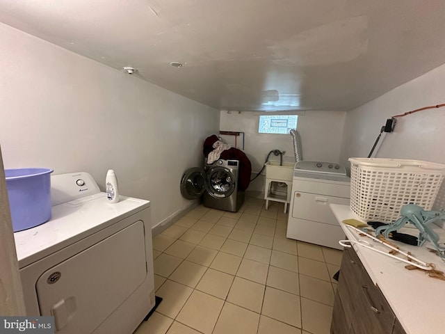 clothes washing area featuring light tile patterned flooring and washing machine and clothes dryer