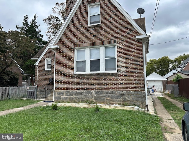 view of side of home featuring a lawn, an outbuilding, and a garage