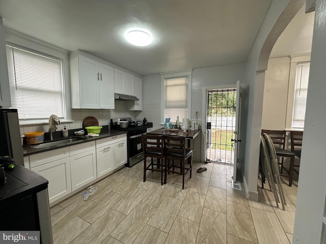 kitchen with white cabinets, stainless steel range oven, sink, and tasteful backsplash