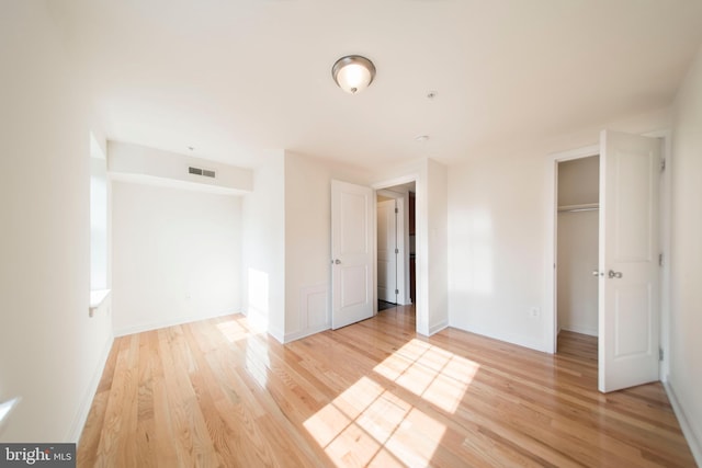 unfurnished bedroom with light wood-type flooring and a closet