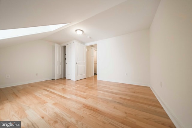 bonus room featuring vaulted ceiling with skylight and light hardwood / wood-style flooring