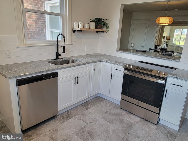 kitchen featuring pendant lighting, stainless steel appliances, sink, and white cabinetry