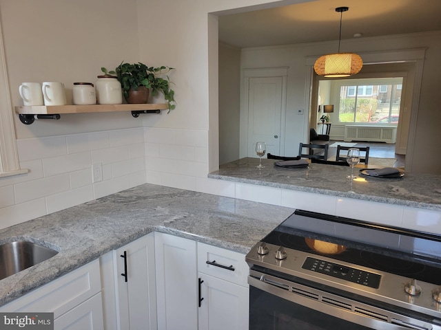 kitchen with decorative light fixtures, stainless steel range with electric stovetop, light stone countertops, and white cabinets