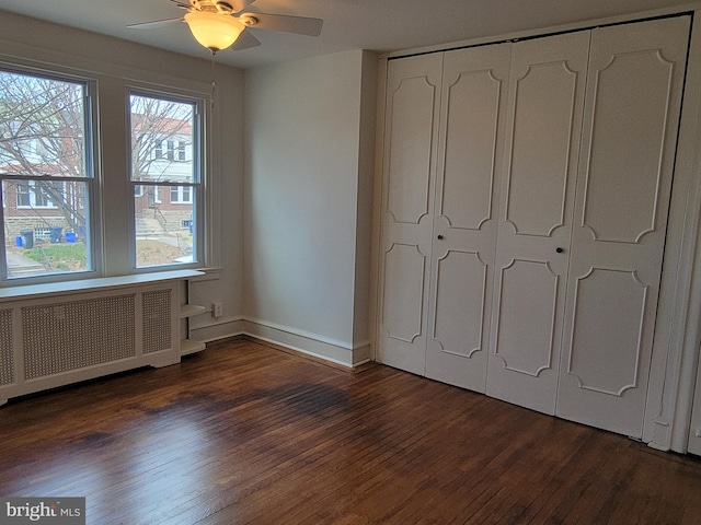 unfurnished bedroom with a closet, radiator, ceiling fan, and dark hardwood / wood-style floors