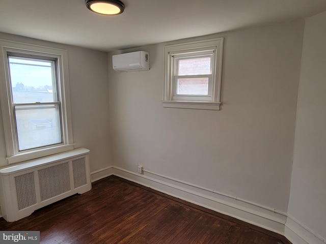 empty room with radiator, dark hardwood / wood-style floors, and a wall unit AC